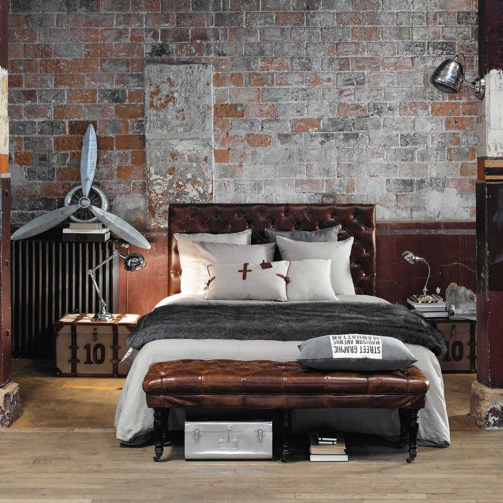 Camera con arredo il stile industriale e cuscini decorativi sopra al letto.