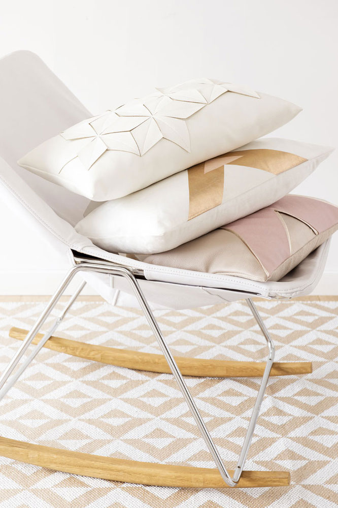 Sedia a dondolo con cuscini geometrici bianco, oro e rosa.