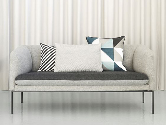 Divano grigio con composizione di cuscini geometrici colori freddi.