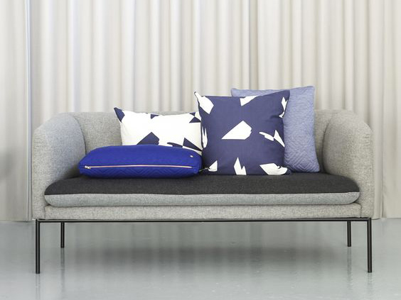 Divano grigio con composizione di cuscini geometrici blu.